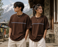Man and woman wearing Manang House brown Himalayan stripe drop-shoulder T-shirts in a mountain village