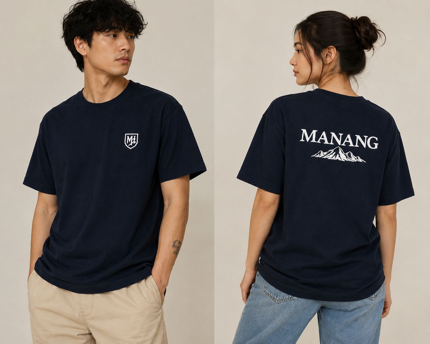 A man and a woman modeling a navy blue short-sleeve t-shirt. The man is shown from the front wearing a small white shield logo on the left chest, and the woman is shown from the back wearing a large white 'MANANG' text graphic with a mountain design.